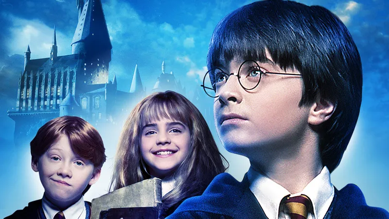 Harry, Hermione e Rony crianças, com o castelo de Hogwarts ao fundo, na arte oficial de Harry Potter e a Pedra Filosofal